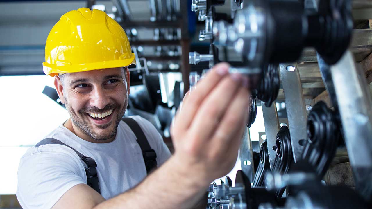 Glücklicher Mitarbeiter eines Maschinenherstellers bei der Einrichtung der Produktion