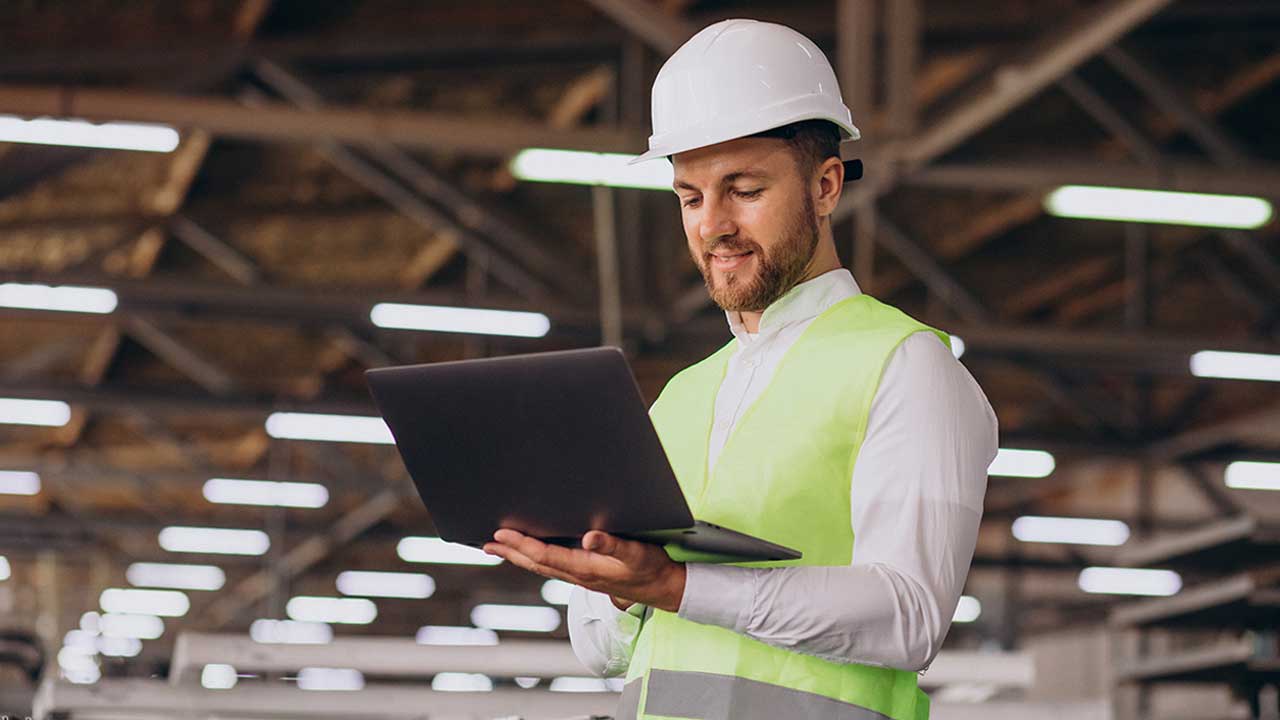 Selbstbewusster Maschinenbauingenieur bei der Arbeit mit FreeCAD in der Produktionshalle